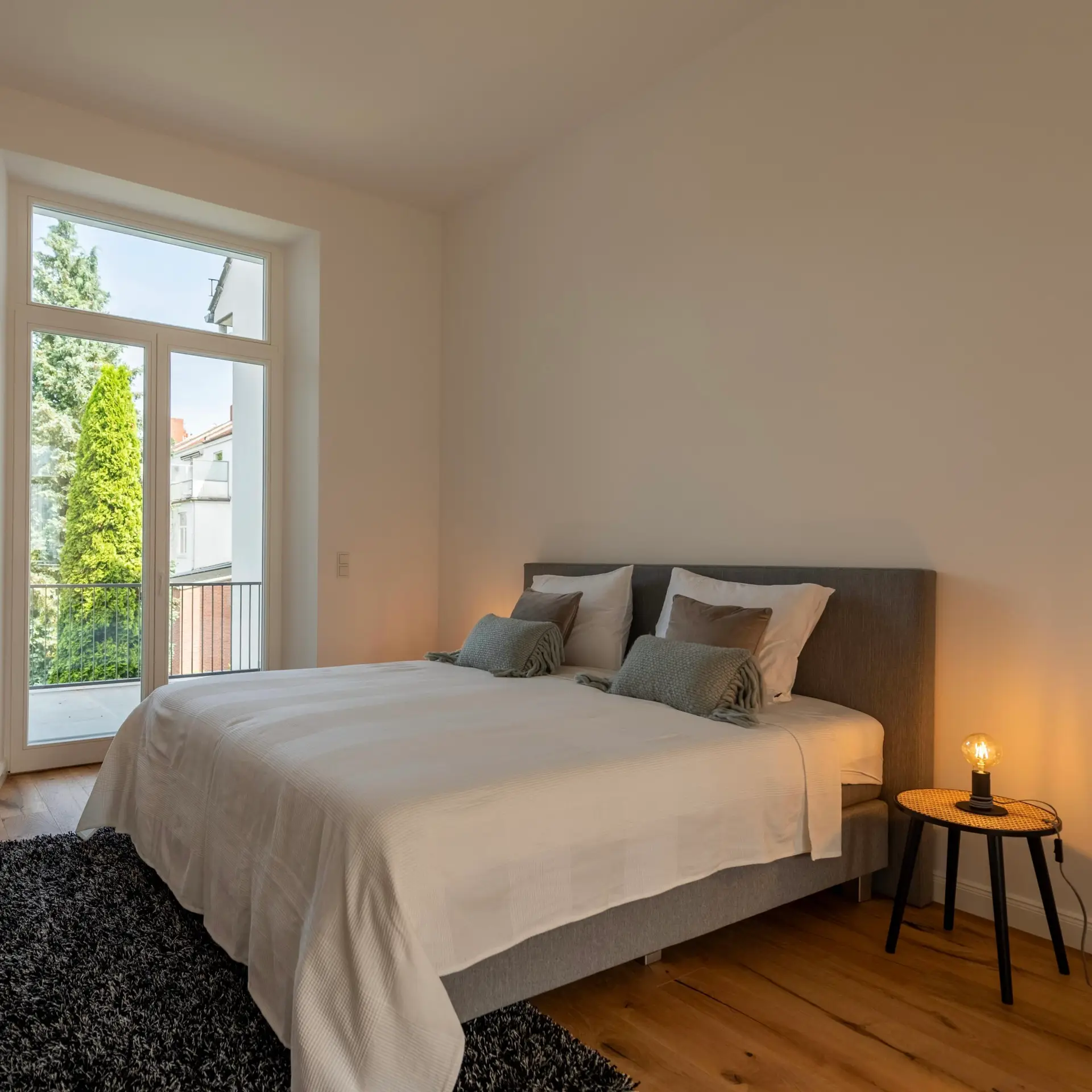 Modern eingerichtetes Schlafzimmer mit Doppelbett und Balkonzugang als Beispiel für Home Staging